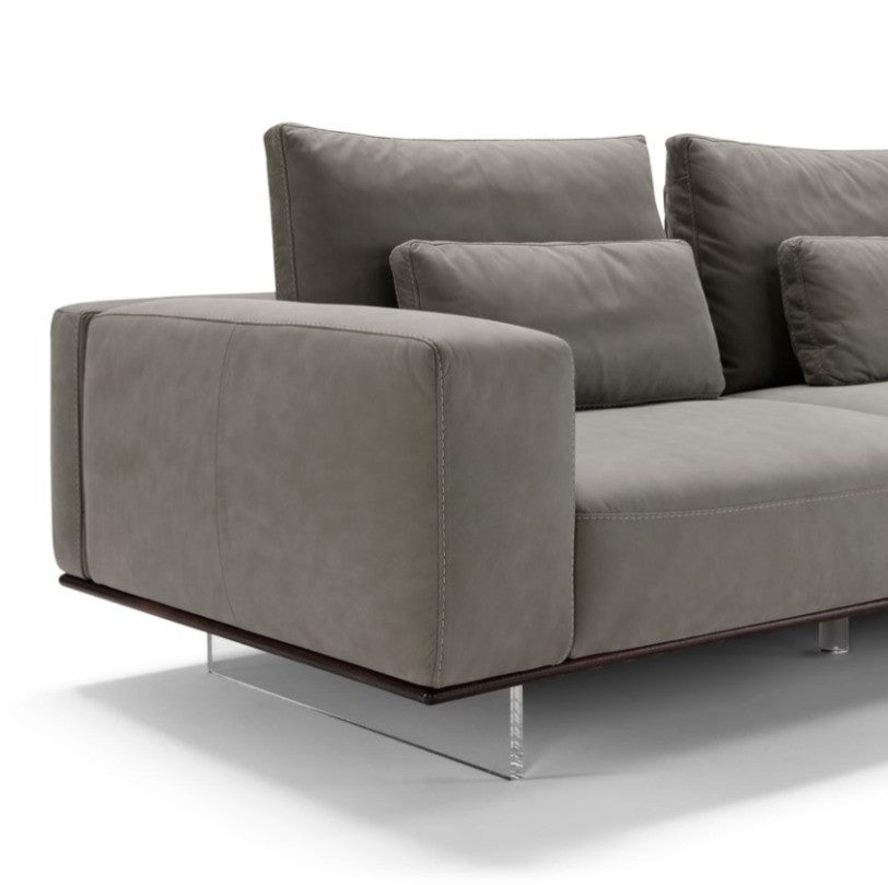 Close-up detail of the sectional sofa's leather armrest, back cushions and plexiglass sled foot