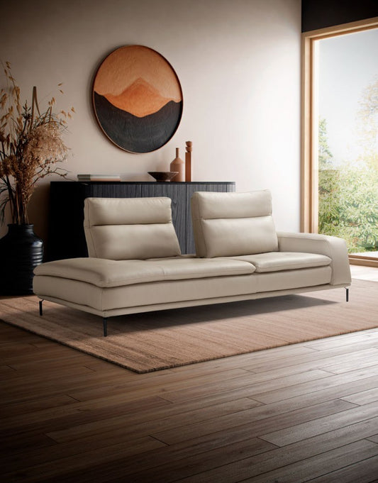 Denise one-arm sofa in beige leather with adjustable back cushions and slim metal feet beside a window