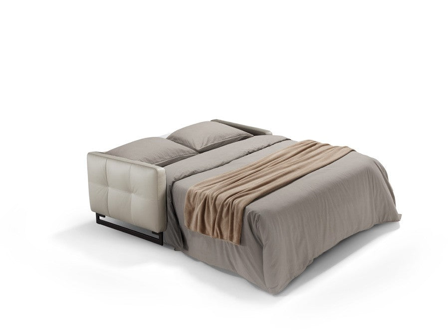 Mal sofa bed fully opened into a bed with mattress, pillows and throw, leather tufted armrest and metal base visible