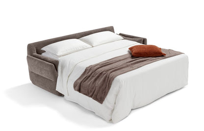 Ambrogio sofa bed opened into a bed with mattress, white bedding, pillows and a brown throw