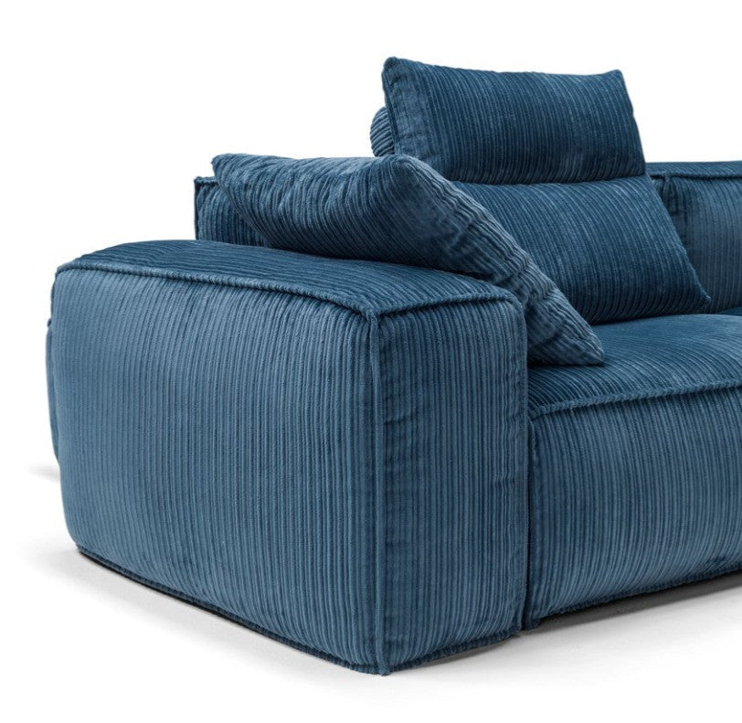 Close-up detail of the corduroy-style upholstery, boxy armrest and loose cushions