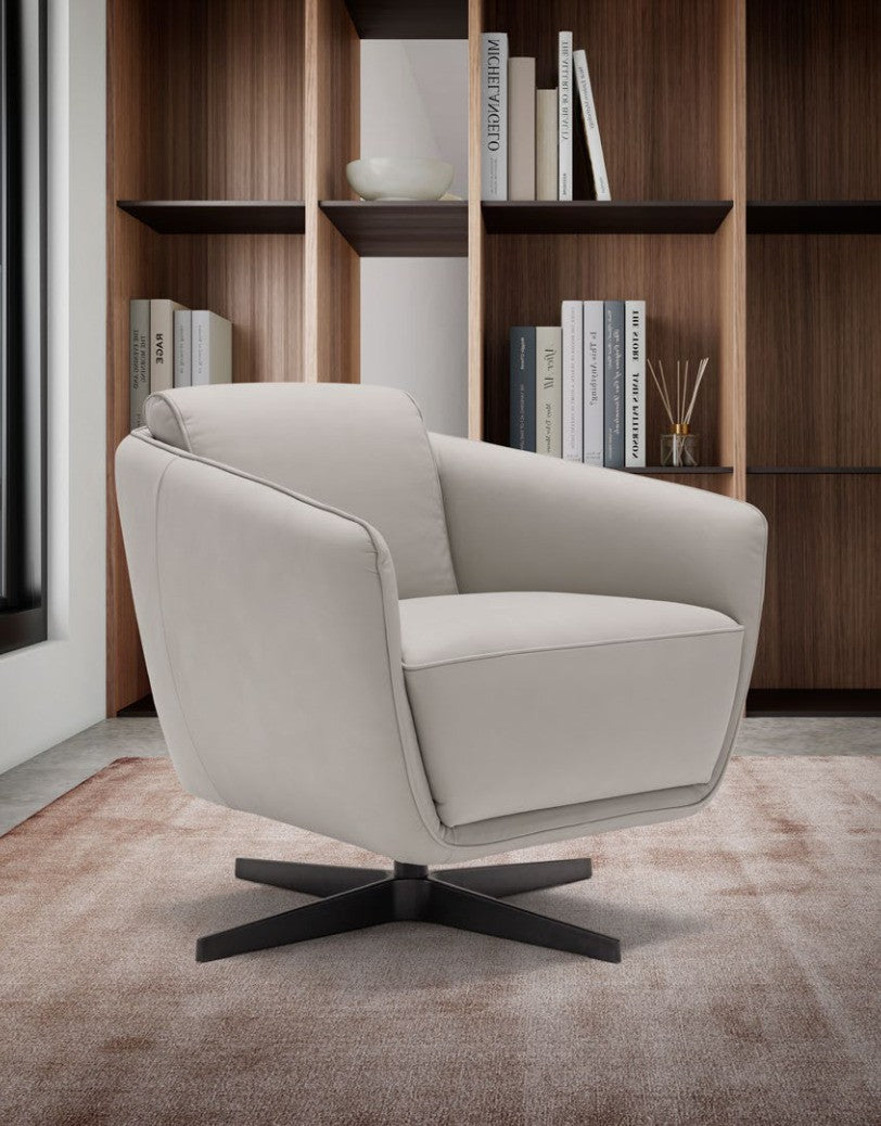 Benati armchair in light grey leather with black metal base, three-quarter view in a library setting with wooden bookshelves