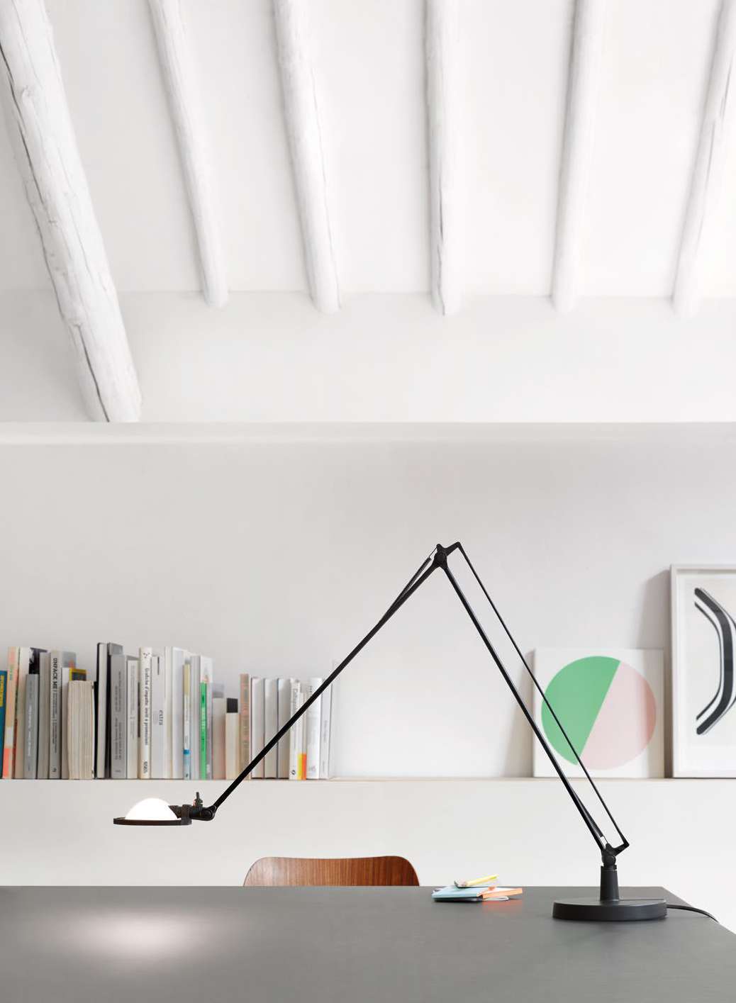 Luceplan Berenice Table Lamp lit on a bookshelf desk