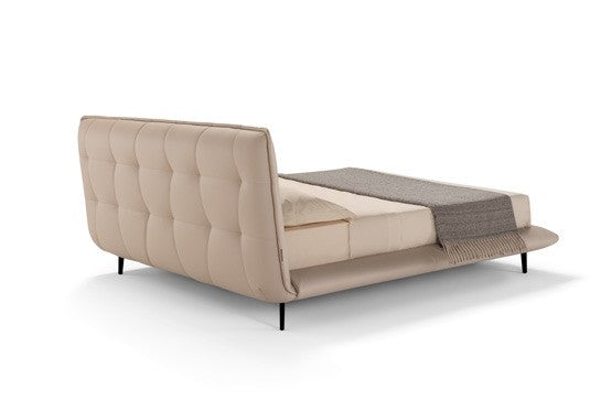 Borg Bed rear three-quarter view showing the tufted back of the curved headboard and slender black metal legs