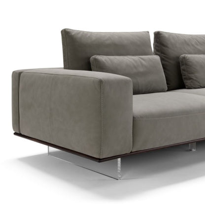 Close-up detail of the sectional sofa's leather armrest, back cushions and plexiglass sled foot
