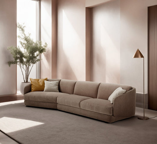 Canto sofa bed in taupe fabric with angled end element in a sunlit living room with a floor lamp and olive tree