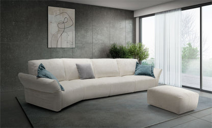 Ivory fabric curved sectional sofa with teal and grey accent pillows against a dark tiled wall