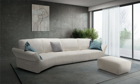 Ivory fabric curved sectional sofa with teal and grey accent pillows against a dark tiled wall