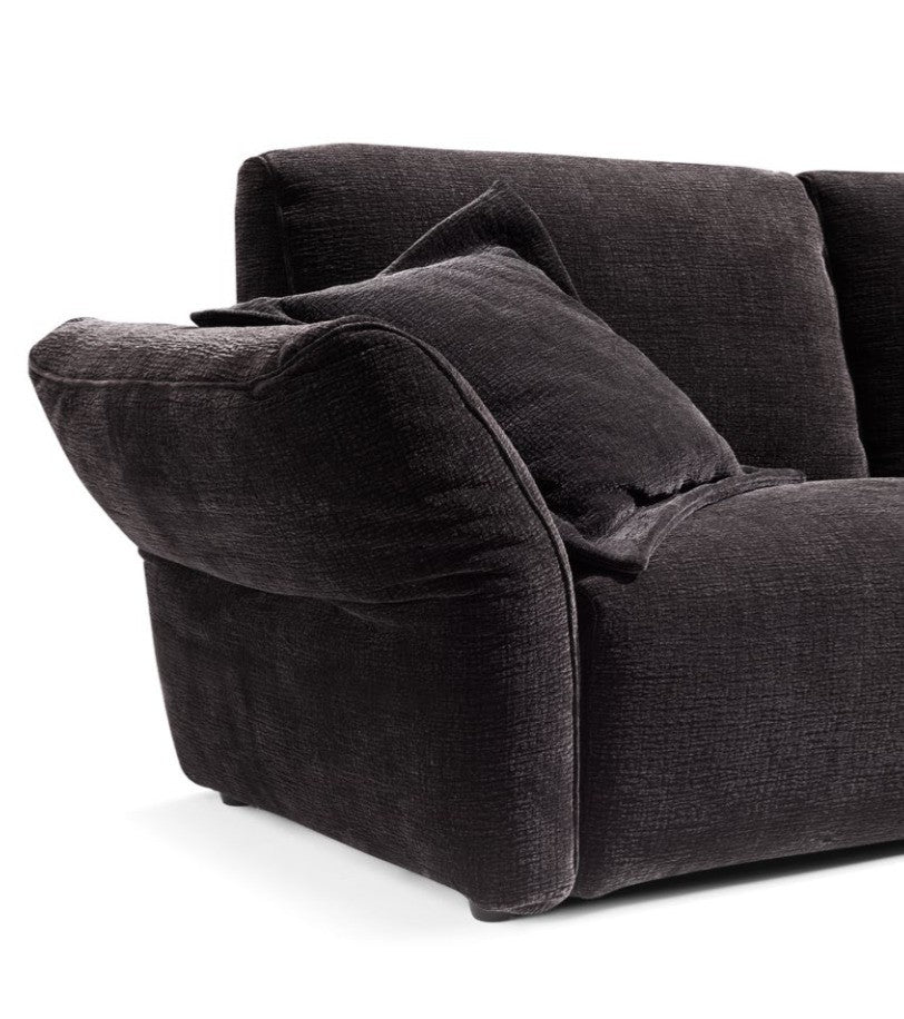 Close-up detail of charcoal grey textured fabric armrest and back cushion with loose accent pillow