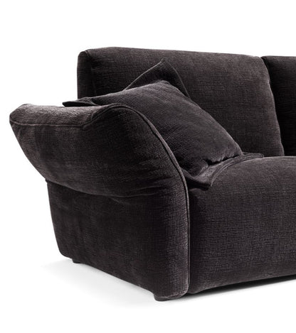 Close-up detail of charcoal grey textured fabric armrest and back cushion with loose accent pillow