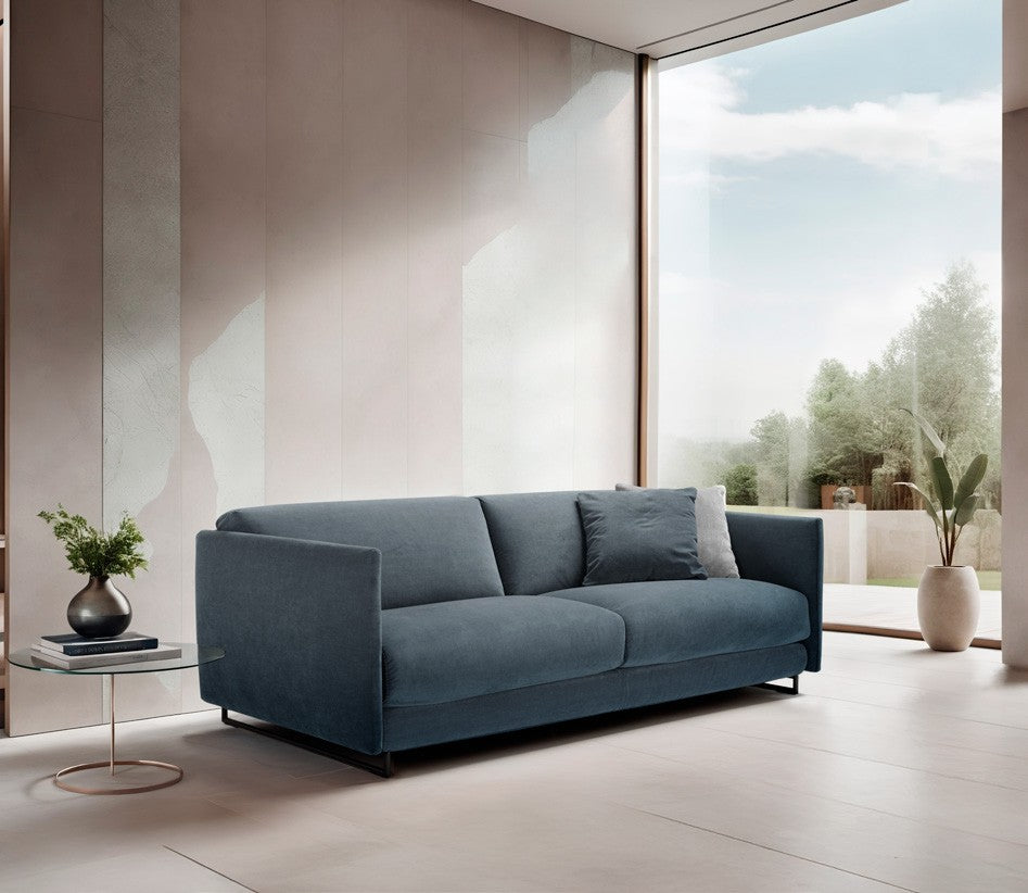 Costa sofa bed in blue fabric with slim metal legs beside a floor-to-ceiling window