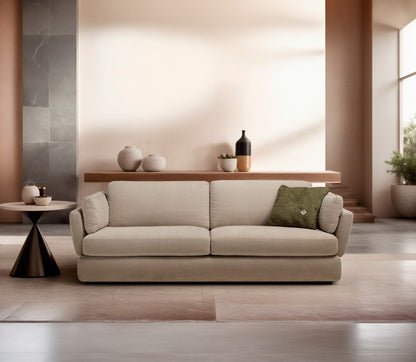 Dambo three-seater sofa bed in beige fabric against a peach wall with a green accent cushion