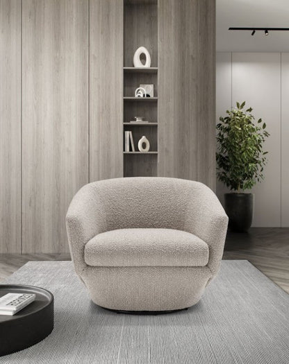 Fracco armchair in textured beige fabric, front view on a striped rug beside a round black coffee table