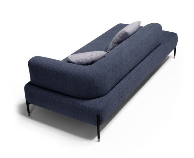 Jordan sofa in navy blue fabric seen from behind, showing the sinuous wraparound backrest and rose gold-tipped metal legs