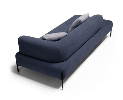 Jordan sofa in navy blue fabric seen from behind, showing the sinuous wraparound backrest and rose gold-tipped metal legs