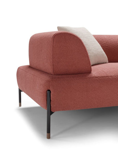 Close-up of the Jordan sofa corner in coral boucle fabric with rounded backrest and black metal leg finished with a rose gold tip