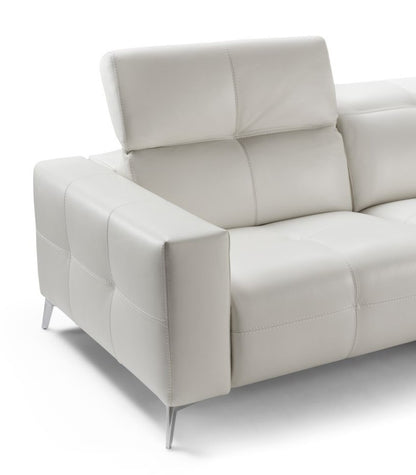 Close-up of the Karma sofa's quilted white leather armrest, raised headrest and slim metal foot