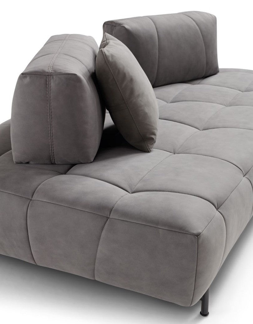 Close-up of the Marvel sofa's quilted grey leather seat with freestanding backrest cushions and slim metal foot