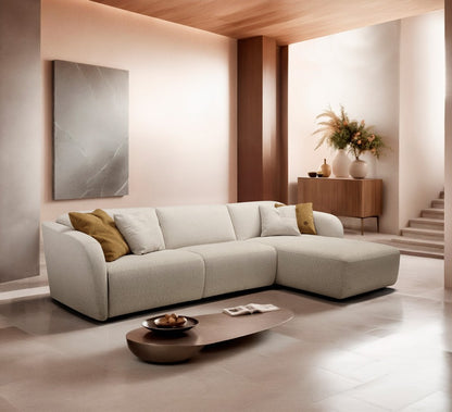 Minerva sofa bed with chaise longue in cream fabric, styled in a warm contemporary living room with a wooden ceiling and oval coffee table
