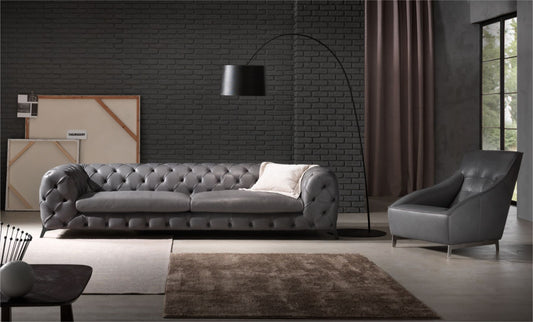 Gray leather Chesterfield-style tufted sofa and matching armchair in a modern living room