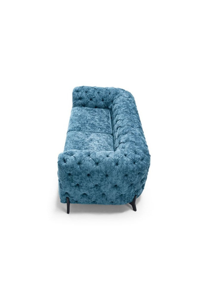 Blue fabric tufted Chesterfield sofa, angled rear view showing deep button-tufted back, on white background