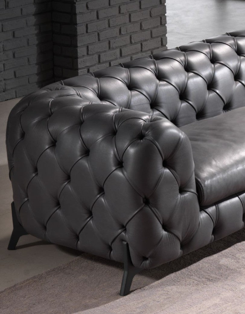 Close-up detail of deep capitonné button-tufted leather upholstery and slim metal leg