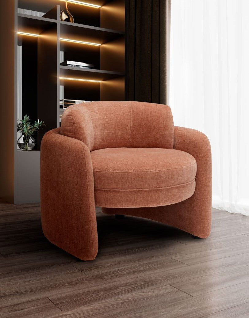 Ringo armchair in terracotta fabric in a contemporary living room with backlit shelving and sheer curtains