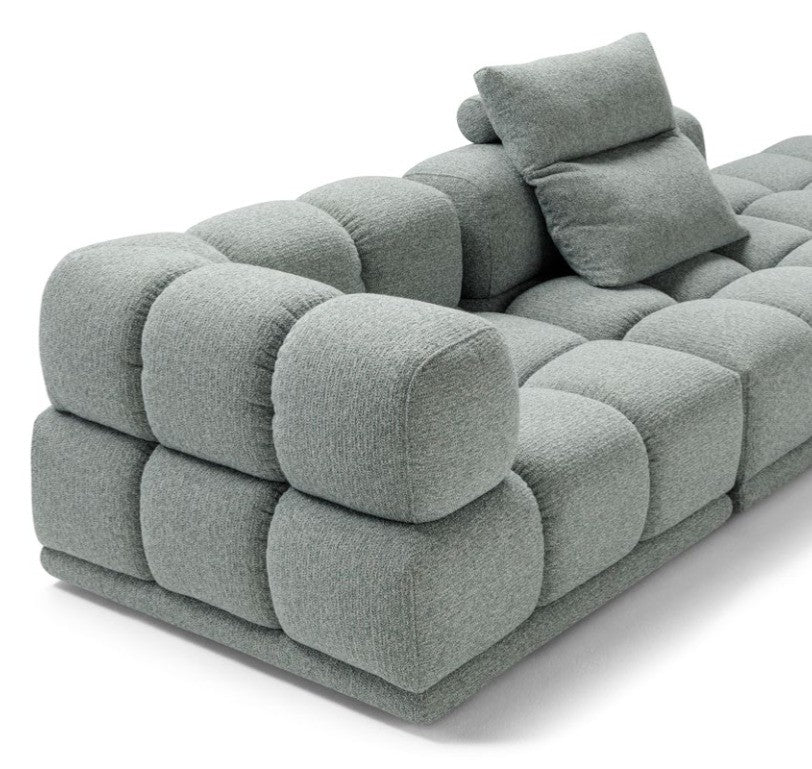 Close-up detail of the Sacai sofa's quilted cushions and loose accent pillow