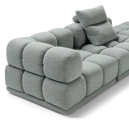 Close-up detail of the Sacai sofa's quilted cushions and loose accent pillow