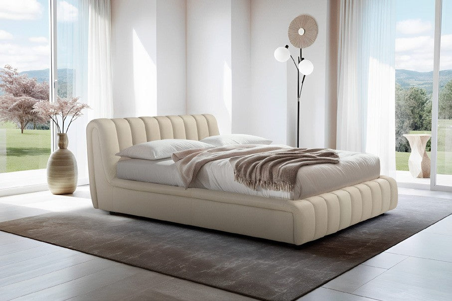 Scervino storage bed in cream upholstery with channel-tufted curved headboard and frame, styled in a bright bedroom with floor-to-ceiling windows