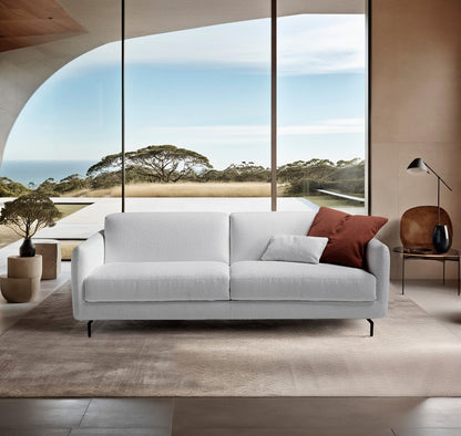 Solar sofa bed in white boucle fabric with slender black metal legs in a bright living room overlooking the sea