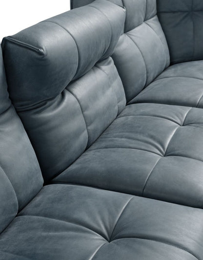 Close-up of the square quilting on the seat, backrest and armrest of the Sospiro sofa in blue-grey leather