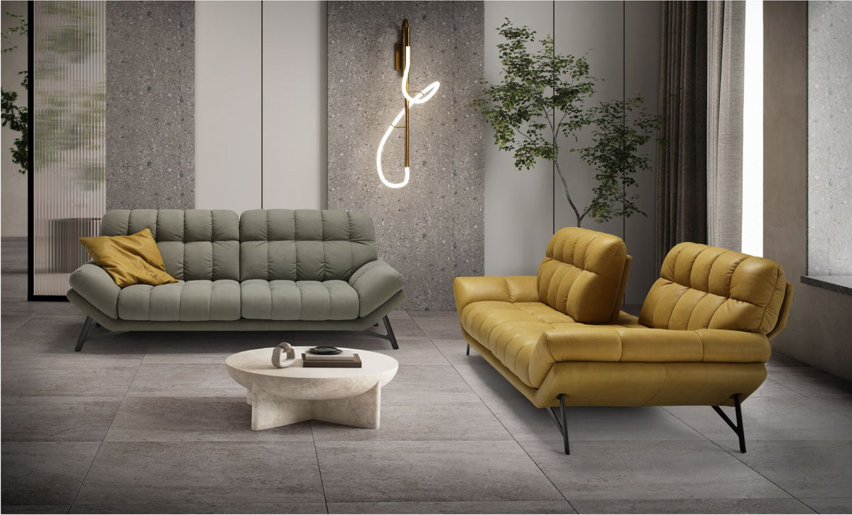 Spiga sofas in grey fabric and mustard leather with quilted seats and angled metal legs around a round stone coffee table