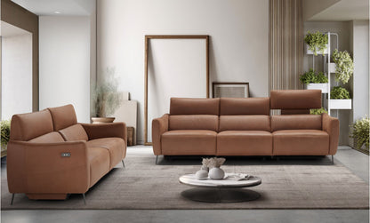 Valentini cognac leather recliner sofas, a two-seater and a three-seater with one headrest raised, in a contemporary living room with a round coffee table and plants